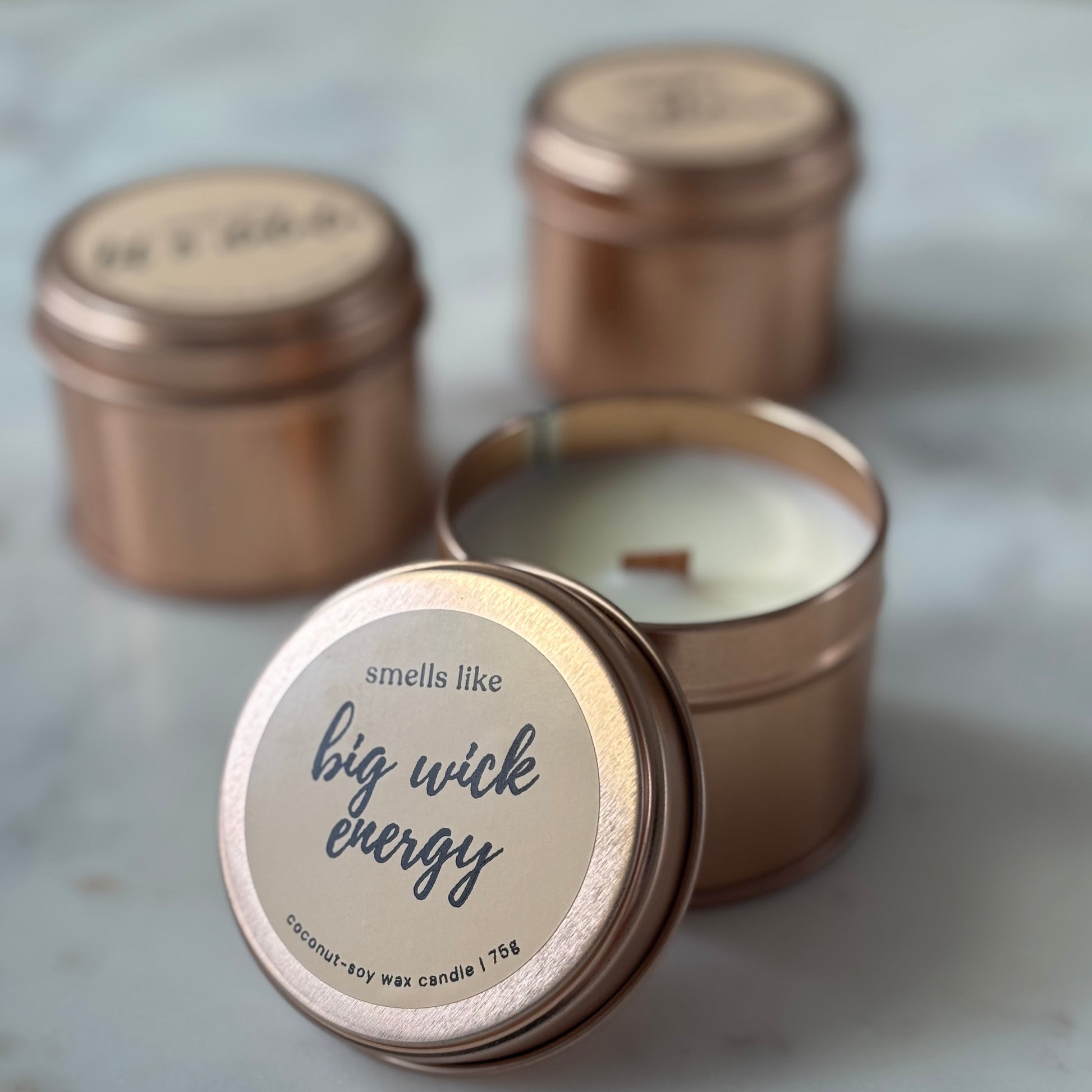 Candle in a bronze tin with a label on a marble surface
